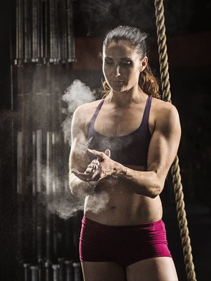 Caucasian athlete chalking her hands in gym