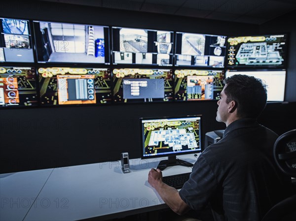 Hispanic security guard watching monitors in control room