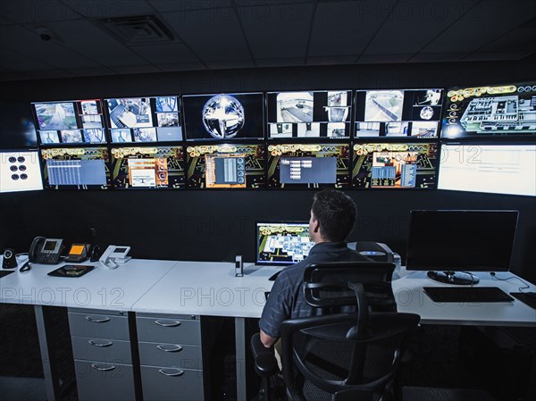 Hispanic security guard watching monitors in control room