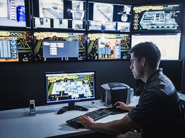 Hispanic security guard watching monitors in control room