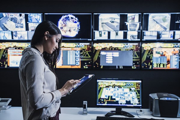 Hispanic security guard using digital tablet in control room