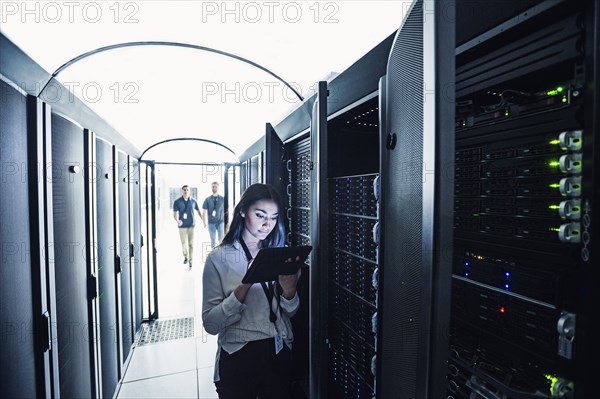 Technician using digital tablet in server room