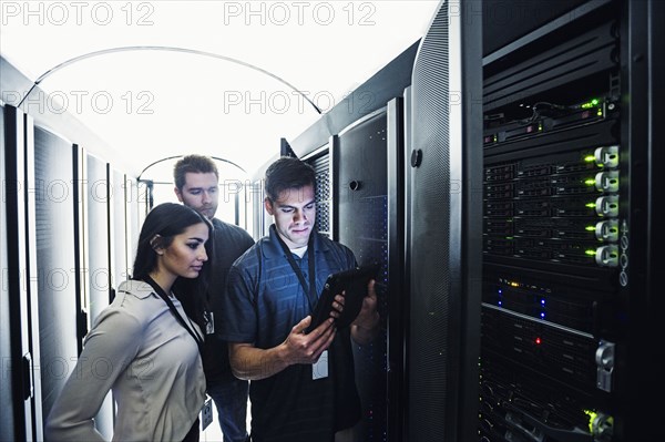 Technicians using digital tablet in server room