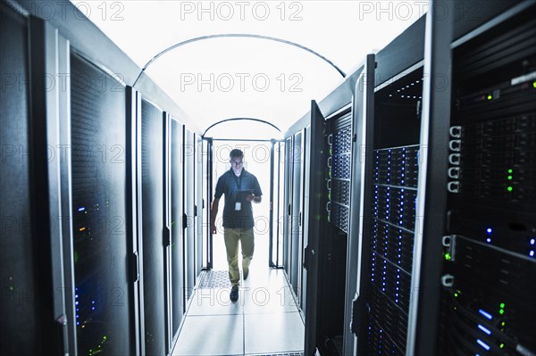 Hispanic technician carrying digital tablet in server room