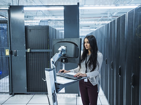 Mixed race technician using computer in server room