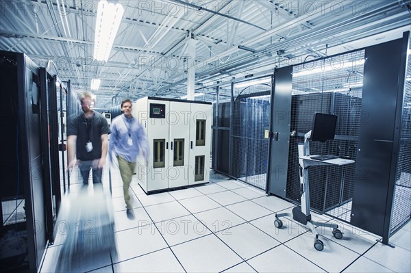 Blurred view of technicians pushing cart in server room