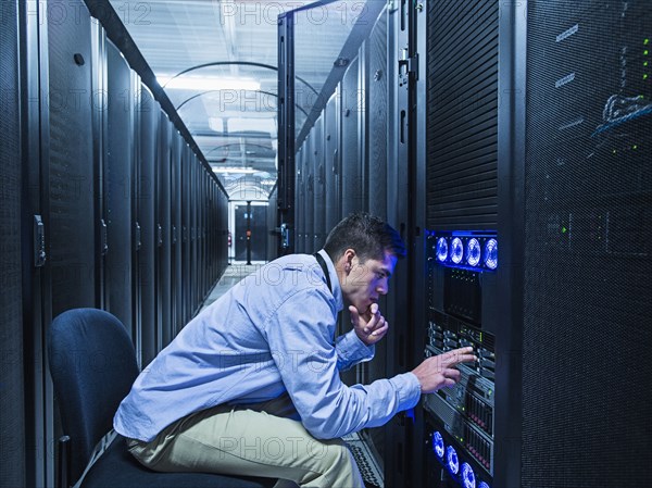 Hispanic technician checking technology in server room