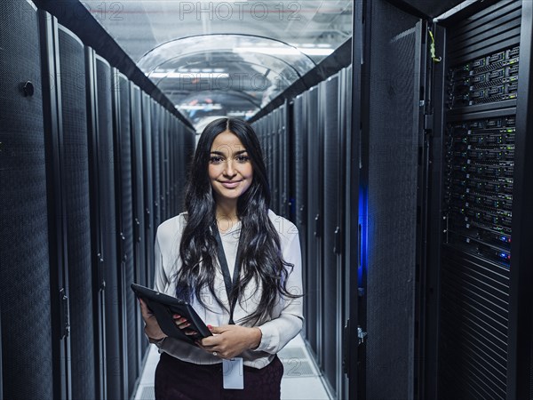 Mixed race technician holding digital tablet in server room