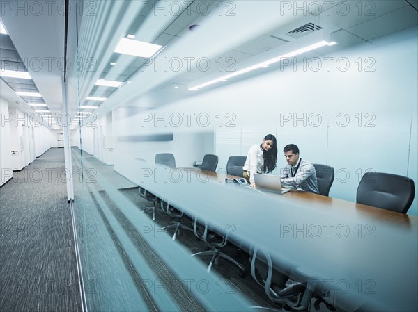 Business people using laptop in conference room