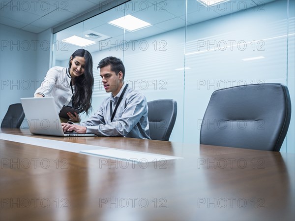 Business people using laptop in conference room