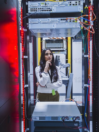 Mixed race technician examining computer in server room