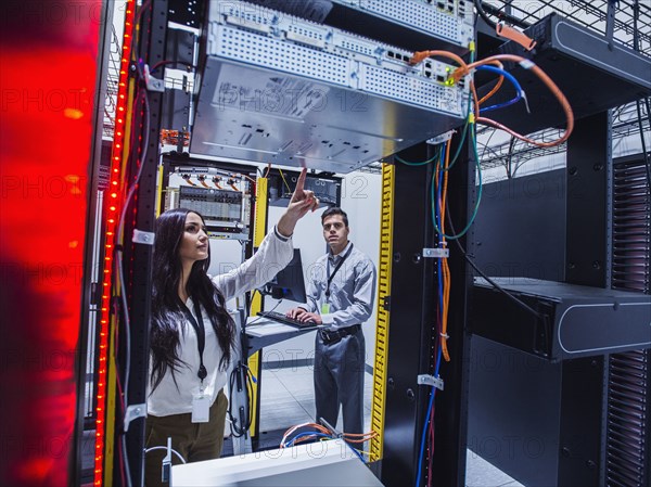 Technicians examining computer in server room