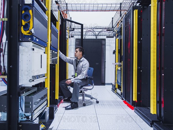 Hispanic technician examining computer in server room