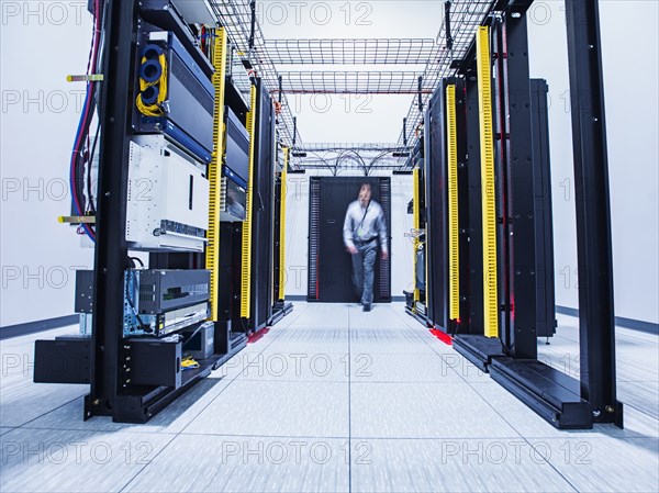 Blurred view of Hispanic technician walking in server room