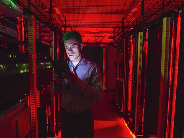 Hispanic technician using digital tablet in server room