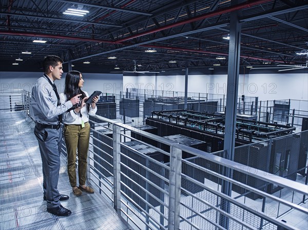 Business people examining server room from balcony