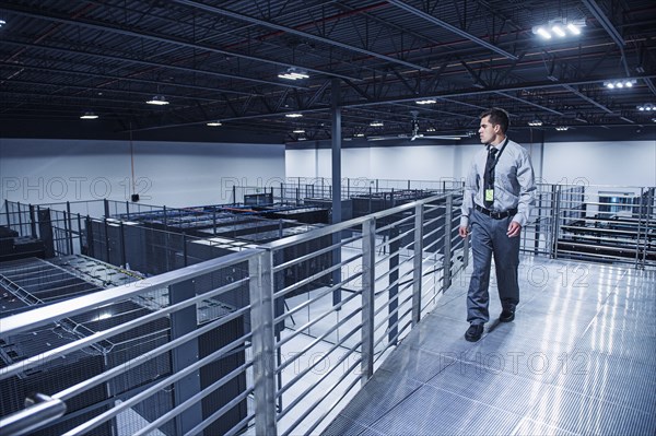 Hispanic businessman examining server room from balcony