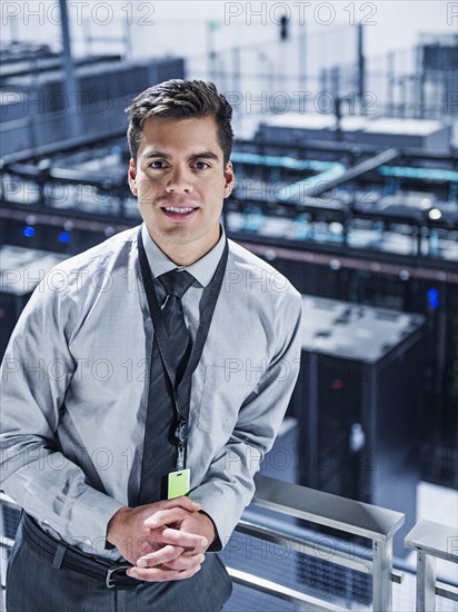 Hispanic businessman standing on balcony over server room