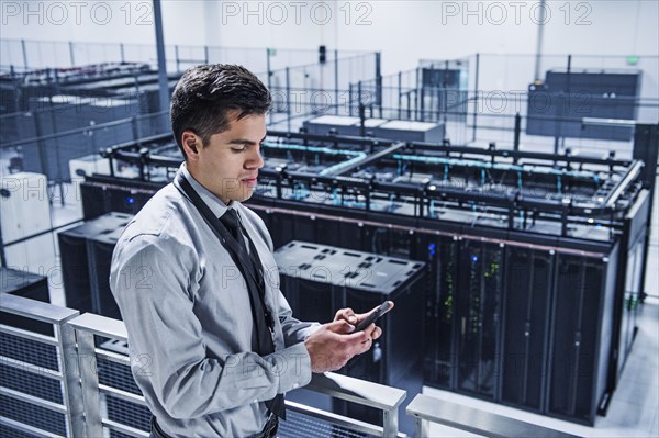 Hispanic businessman using cell phone on balcony over server room