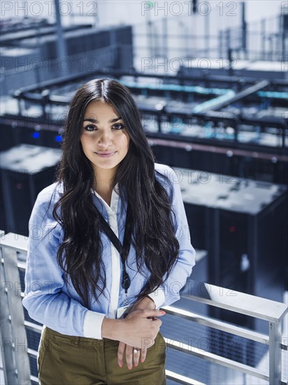 Mixed race businesswoman smiling on balcony over server room