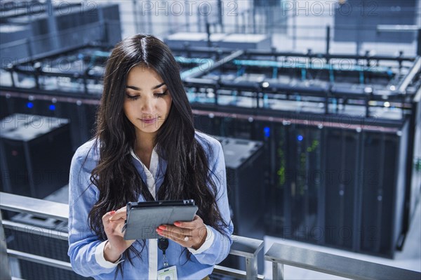 Mixed race businesswoman using digital tablet on balcony over server room