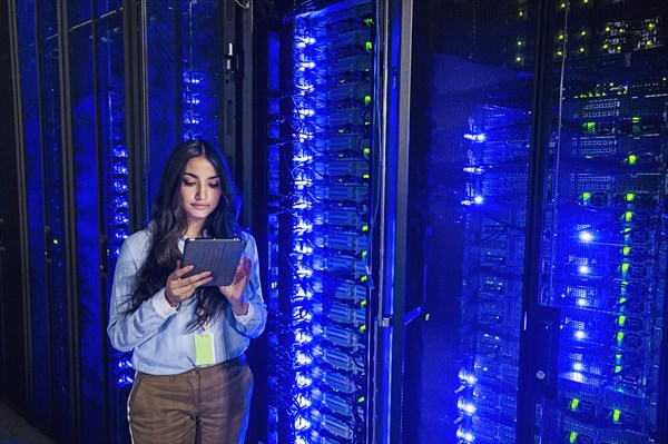 Mixed race technician using digital tablet in server room