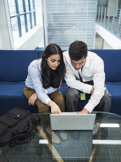 Business people using laptop in office lobby