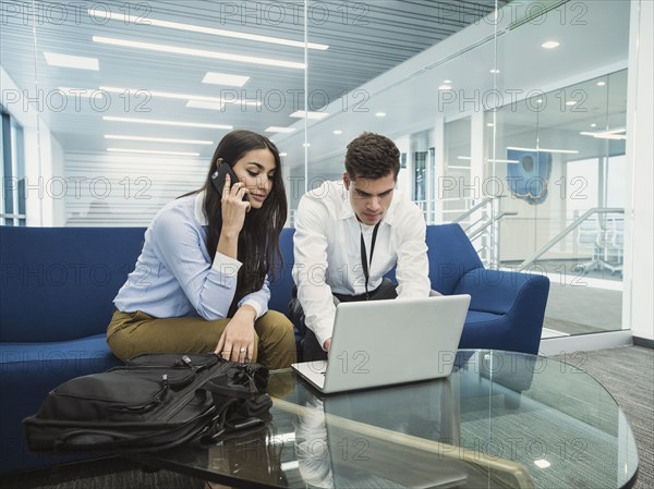 Business people using laptop in office lobby