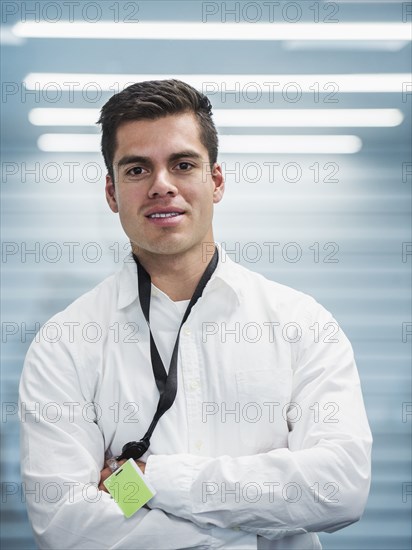 Hispanic businessman standing with arms folded in office