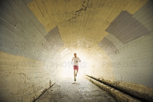 Caucasian man jogging in tunnel