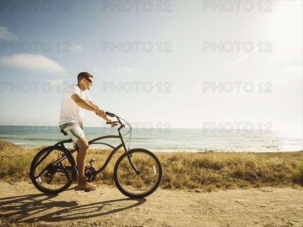 Caucasian man riding bicycle on beach