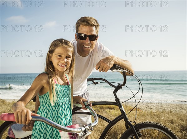 Caucasian father and daughter riding bicycles on beach