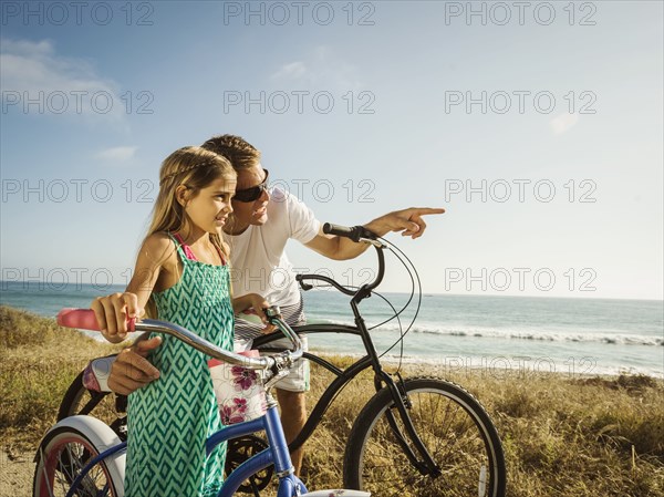 Caucasian father and daughter riding bicycles on beach