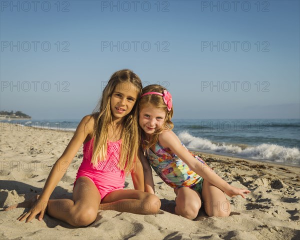 Caucasian sisters smiling on beach