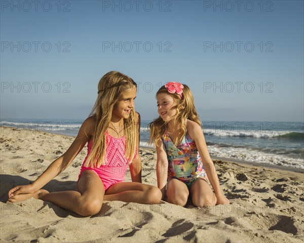 Caucasian sisters smiling on beach