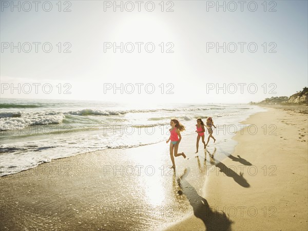 Caucasian sisters running on beach