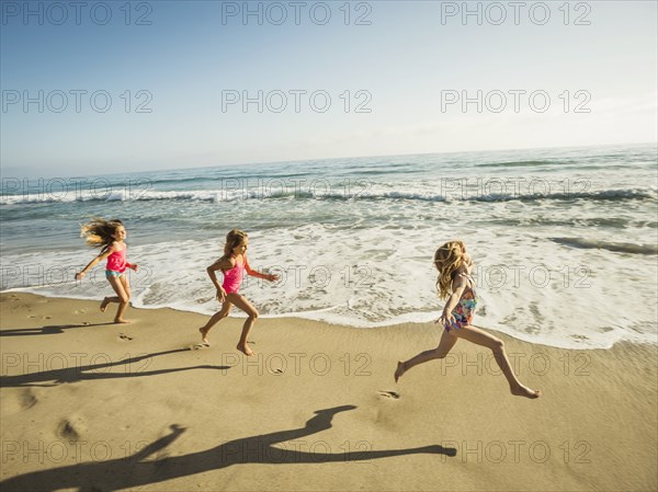 Caucasian sisters running on beach