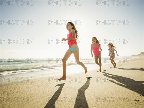 Caucasian sisters running on beach