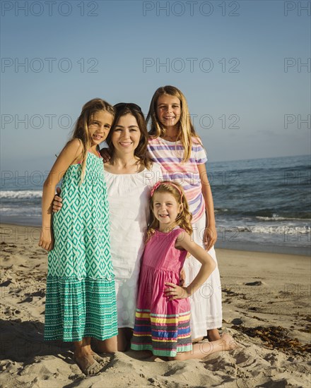 Caucasian mother and daughters smiling on beach