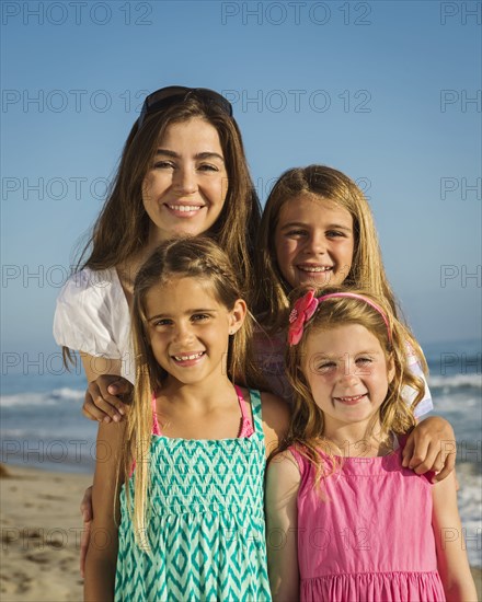 Caucasian mother and daughters smiling on beach