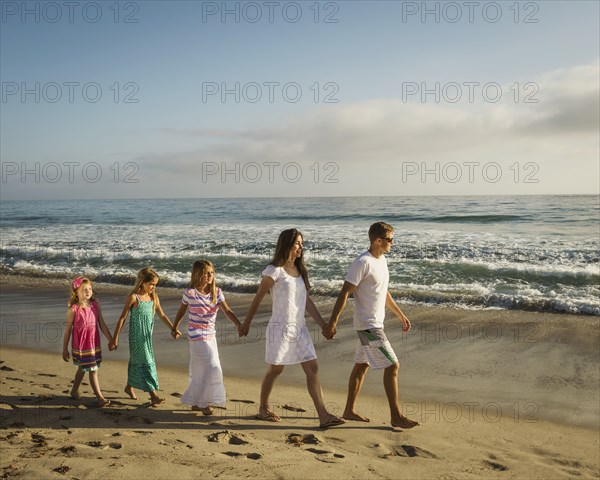 Caucasian family holding hands on beach