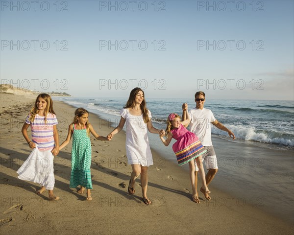 Caucasian family holding hands on beach