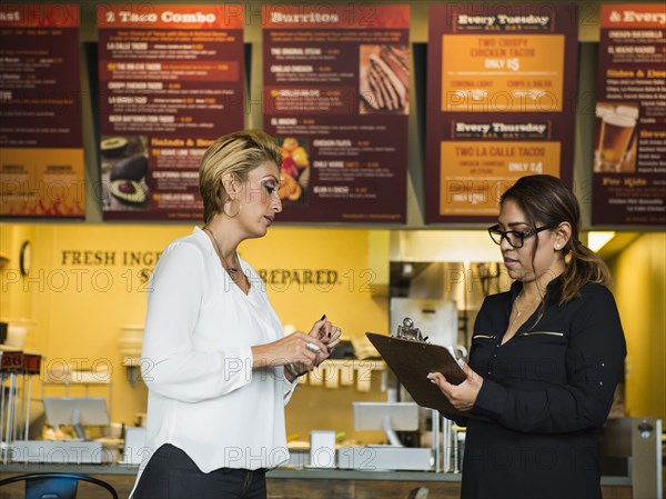 Hispanic business owner talking to employee in cafe