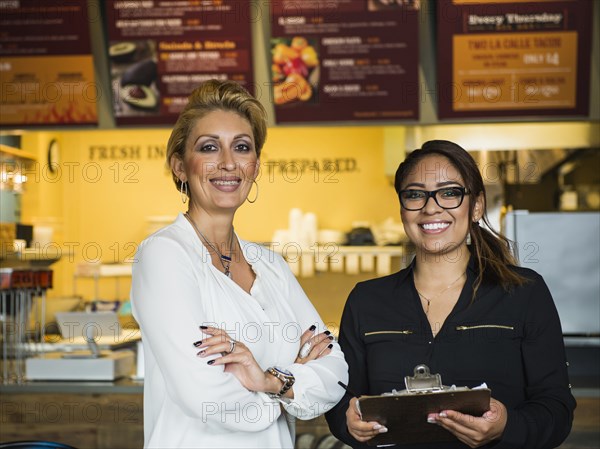 Hispanic business owner and employee smiling in cafe