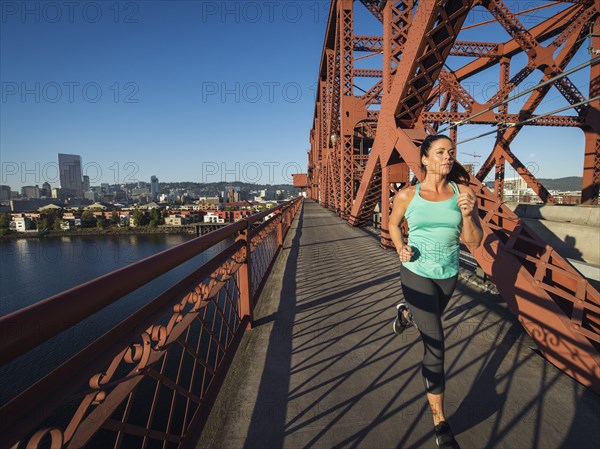 Caucasian woman jogging on urban bridge