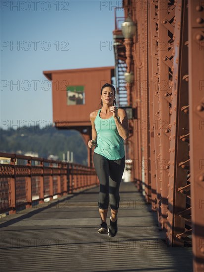Caucasian woman jogging on urban bridge