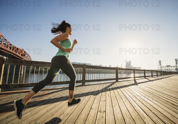 Caucasian woman jogging on urban waterfront