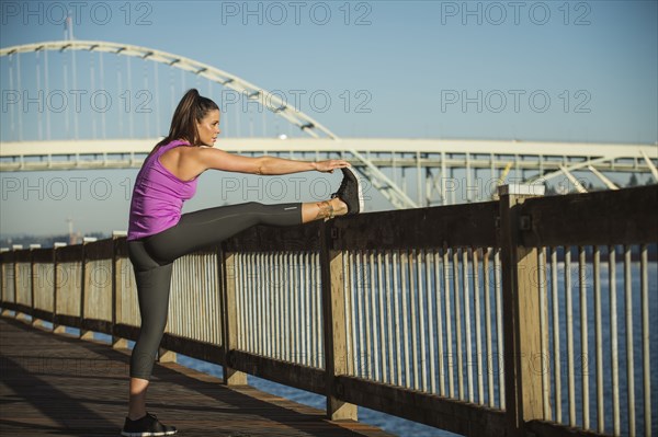 Caucasian woman stretching on urban bridge