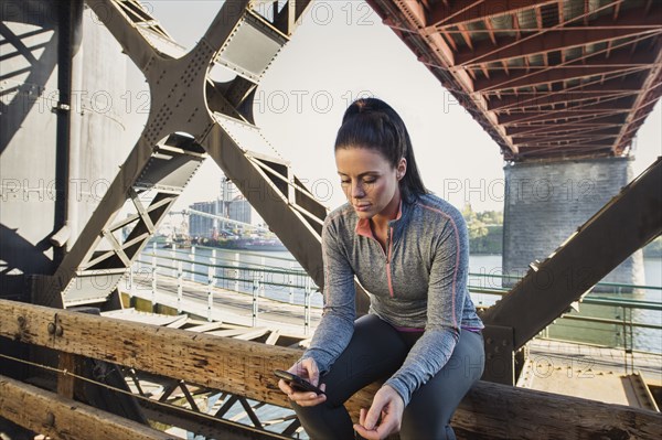 Caucasian woman sitting on urban bridge