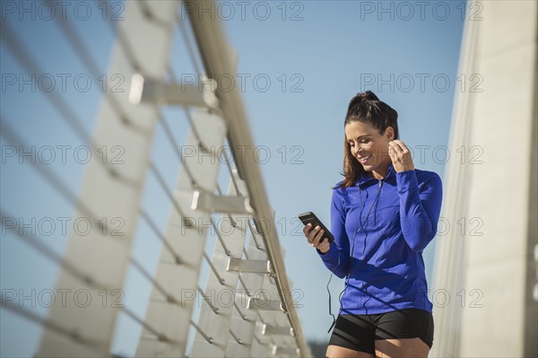 Caucasian woman using cell phone on urban bridge